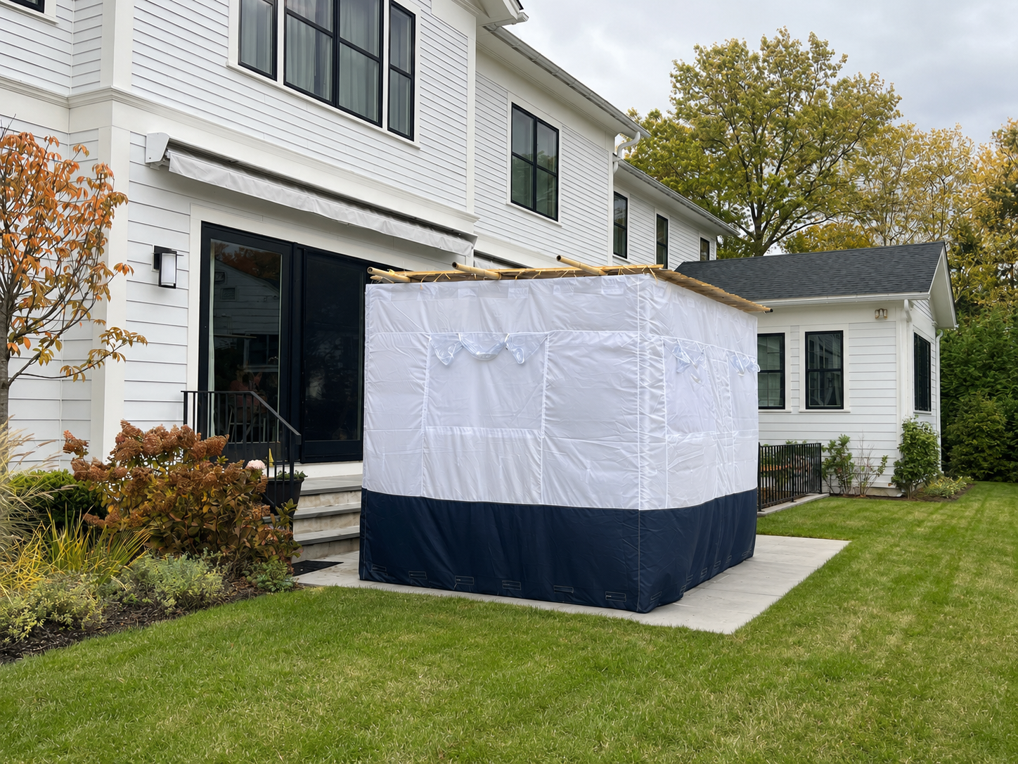 Completed residential sukkah with white walls, clear windows, and a dark lower panel