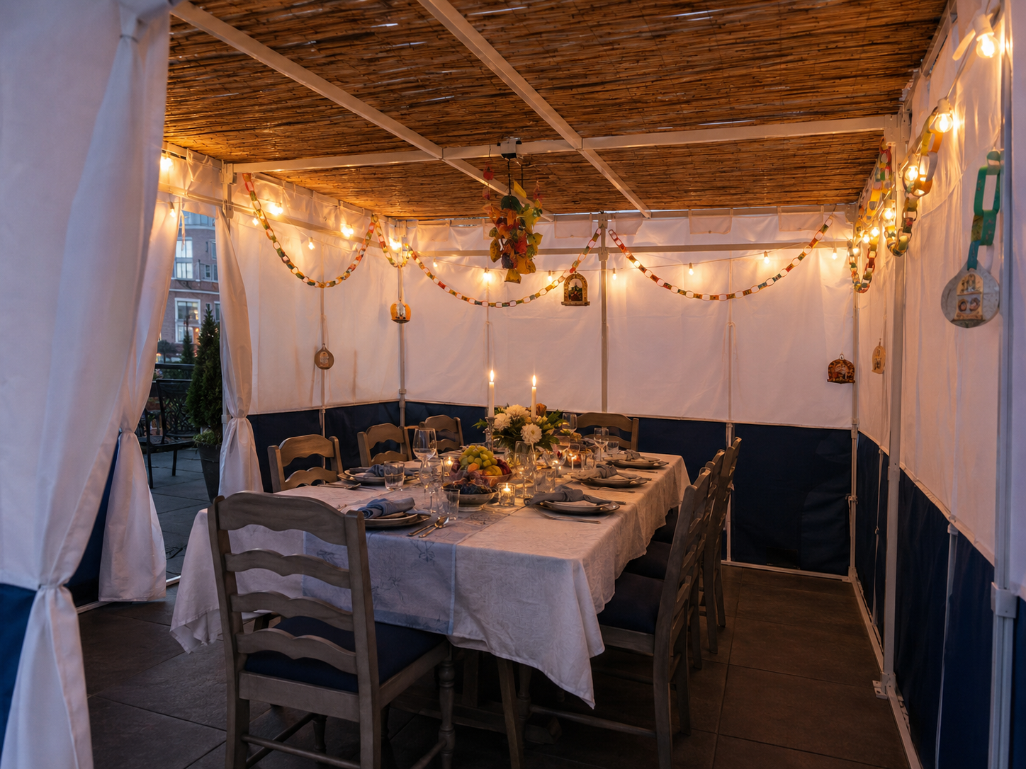 Fully furnished and decorated residential sukkah with holiday dining table, lighting, seating, and bamboo schach